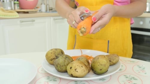 Woman Peels Carrot and Potatoes in Kitchen