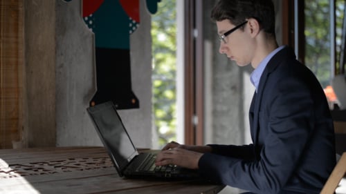 Young Adult Works on Laptop in Modern Office