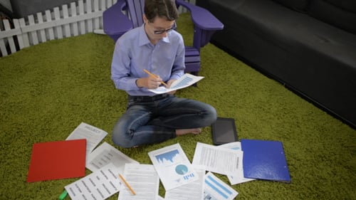 Young Adult Analyzes Data at Home on Rug