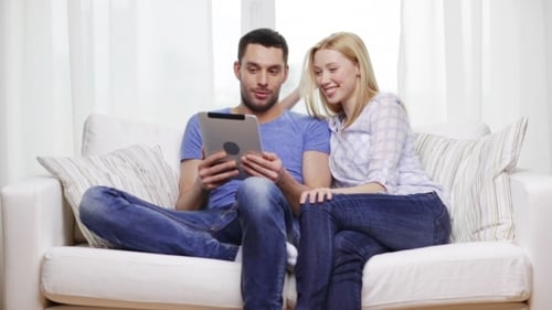 Young Couple Relaxing on Couch with Tablet