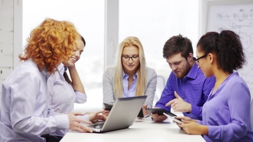 Equipe sorridente com computadores portáteis e de mesa