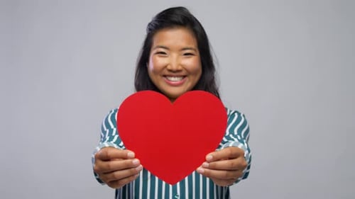 Smiling Young Woman Holds Red Paper Heart
