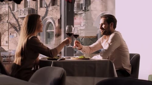 Young Couple in Love Enjoying Romantic Date in Cafe Clinking with Wine Glasses