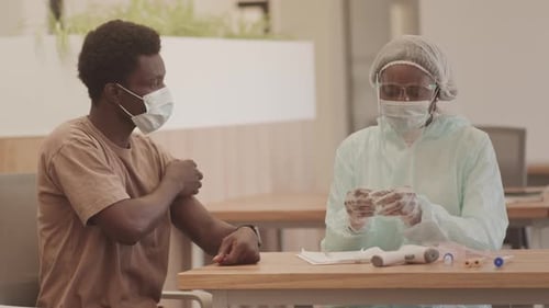 Man Receiving Injection from Health Professional at Table