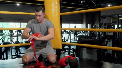 Male Fighter Preparing for Boxing Wrapping His Fists in Bandages