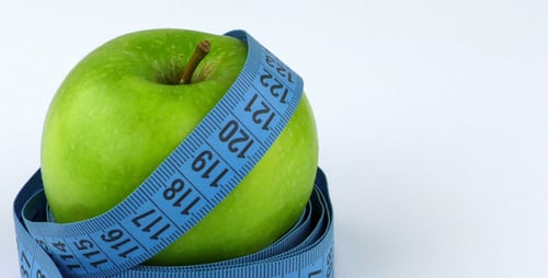 Green Apple Wrapped in Measuring Tape on White