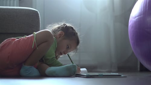 Girl Drawing in Notebook on Living Room Floor