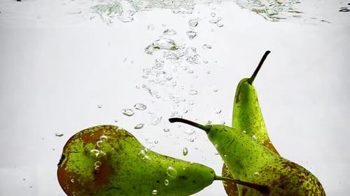 The Green Pear Sinks Into the Water with Bubbles on Isolated White Background, Video Recording