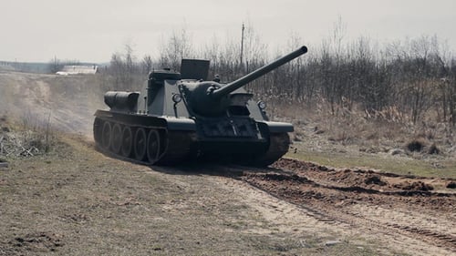 Military Tank Drives on Dirt Road in Rural Area