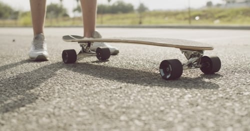 Person Prepares to Skateboard on Paved Road