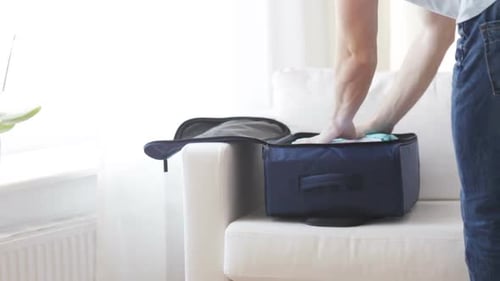 Close Up Of Man Packing Clothes Into Travel Bag