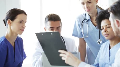 Group Of Doctors With Clipboard Talking At Clinic 2