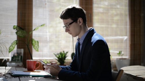 Young Adult Using a Smartphone at a Table