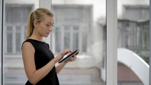Woman Using Tablet Indoors by Large Window