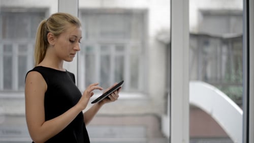 Woman Uses Tablet Device Indoors by Window