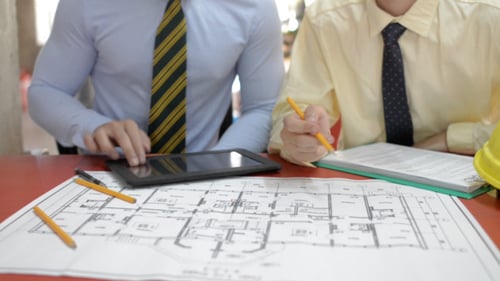 Architects Reviewing Building Plan with Tablet and Pencil