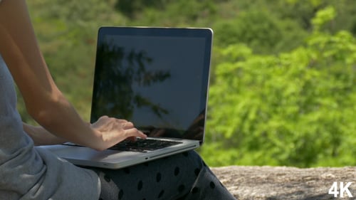 Young Adult Typing on Laptop Outdoors