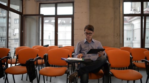 Young Adult Student Using Tablet in Empty Classroom