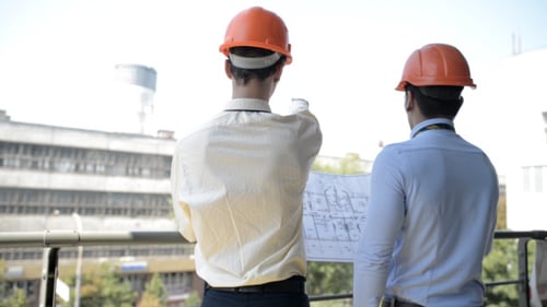 Engineers Look at Architectural Plans on Balcony