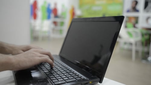 Hands Typing on Laptop Keyboard in Office