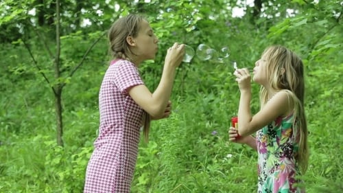 Young Girls Blowing Soap Bubbles Outdoor