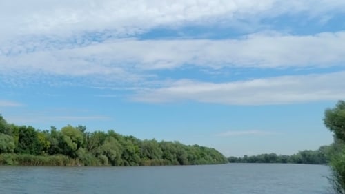 Weiße, flauschige Wolken über dem Fluss