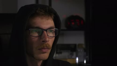 Der
fokussierte junge männliche Programmierer in Brillen benutzt nachts einen Laptop im dunklen Raum.