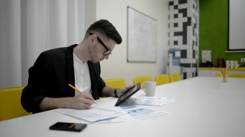 Young Adult Works with Tablet at Conference Table