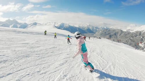 Snowboarderin auf Snowboard läuft im Skigebiet die Piste hinunter