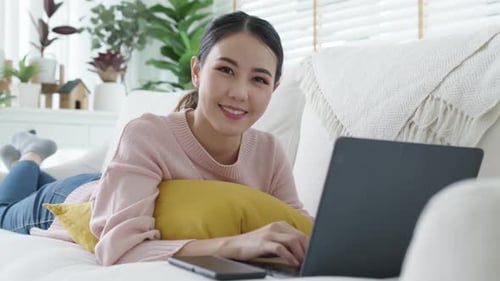 Woman Works on Laptop Relaxing on Couch at Home