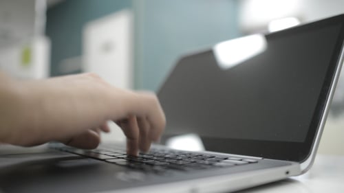Hands Typing on a Laptop in an Office