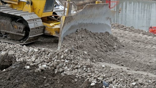 Un bulldozer poussant des pierres sur la route