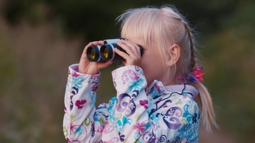 Girl Exploring Nature with Binoculars in Wooded Area
