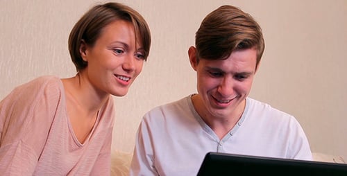 Smiling Couple Looking at Laptop Together Indoors