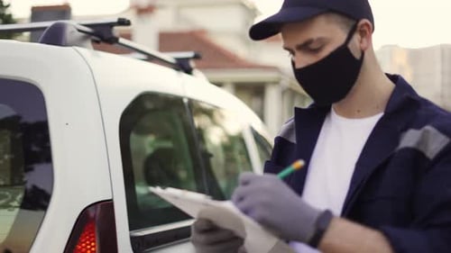 Hübscher Kurier, der aus dem Van geht und das Kartonpaket aus der Lieferung nimmt, Automarken