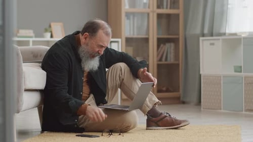 Senior Man Using Laptop and Talking on Smartphone