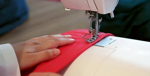 Hands Sewing Red Fabric with Sewing Machine