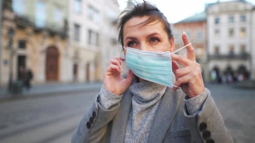 Woman Puts On Face Mask in City