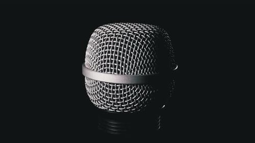 Le microphone pivote sur fond noir. La grille dynamique du microphone tourne en gros plan