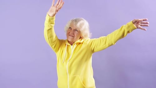 Senior Woman Dances Joyfully in Yellow Jacket