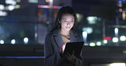 Young Woman Uses Tablet at Night in City