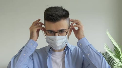 Young Adult Puts On Disposable Face Mask