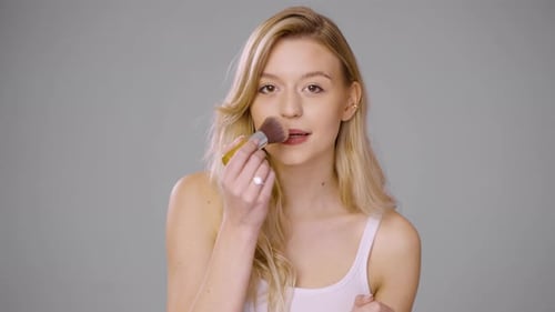 Young Woman with Brush Applying Makeup