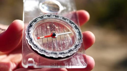 Close up on the needle spinning of a magnetic compass finding north on a hike to stay on the trail a
