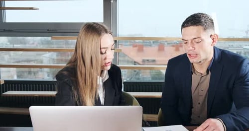 Man and a Woman Discussing Work in the Brightly Lit Modern Office. Concerned Male and Female Working