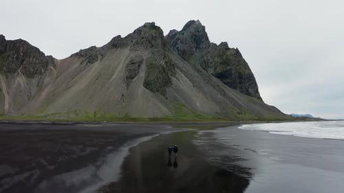 Drone Of Men Walking Along Black Beach To Vestrahorn Mountain
