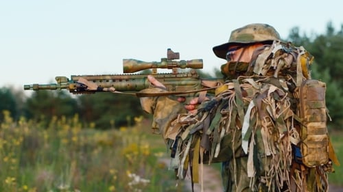 Soldier in Camouflage Gear Holding Rifle in Field