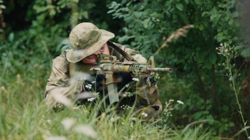 Adult Aiming Rifle in Camouflage in Grassy Area