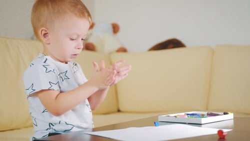 Cute Child Prepares to Draw Indoors at Table