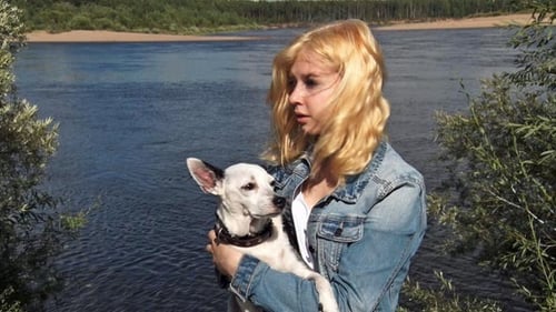 Woman Holding Dog By River on Sunny Day